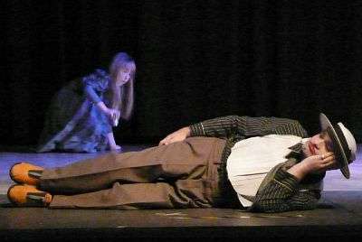 Foto: Szene aus dem Stück "Fünf kurze Spiele über die Liebe" - Schlafender Schauspieler vorne auf der Bühne, ein junges Mädchen im Hintergrund