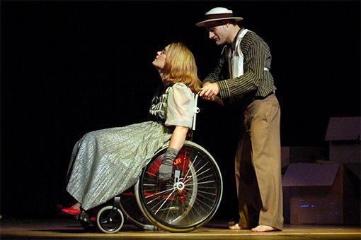 Foto: Szene aus dem Stück "Fünf kurze Spiele über die Liebe" - Schauspieler schiebt eine Schauspielerin, die im Rollstuhl sitzt